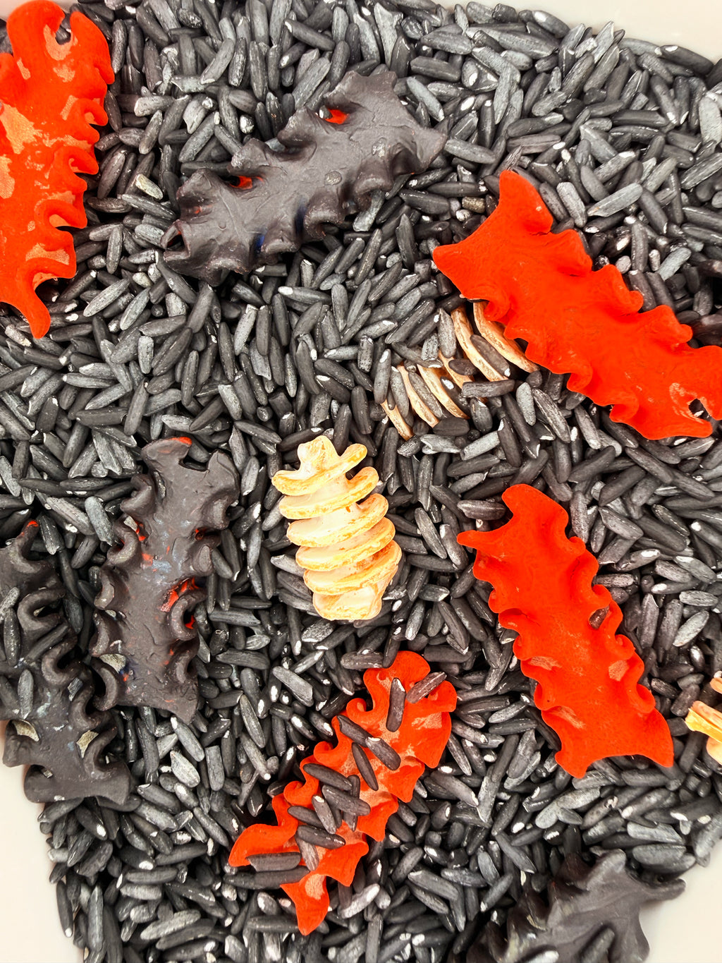 Close-up of the Zombie Bones sensory mix showing black rice, Halloween bone pasta and textured sensory materials.